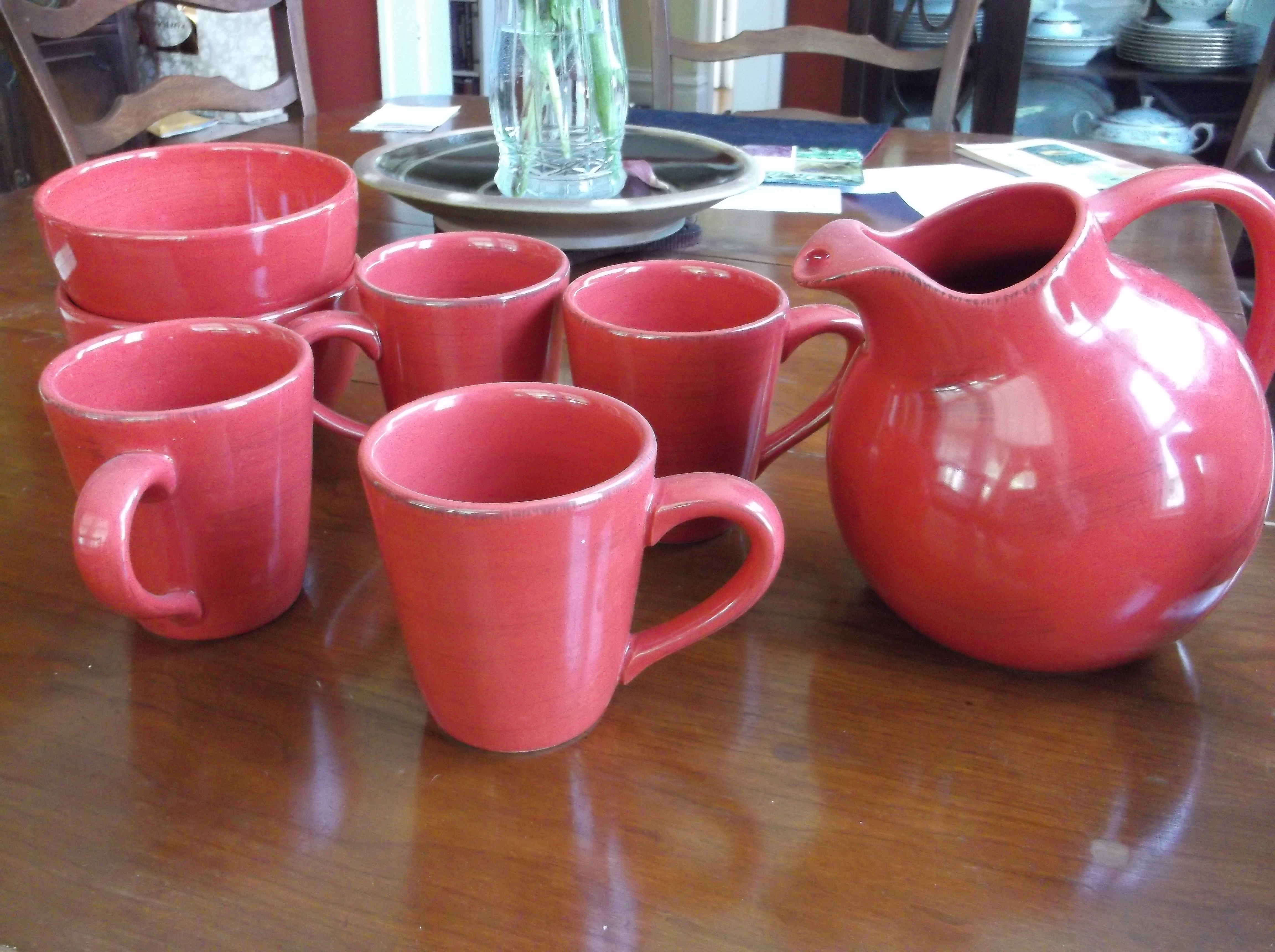 Red mug-and-pitcher set and two red bowls that happen to match them - for sale.